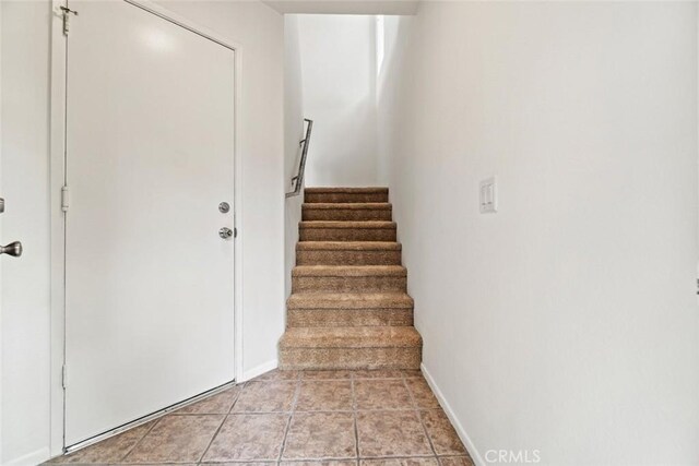 staircase featuring baseboards and tile patterned flooring