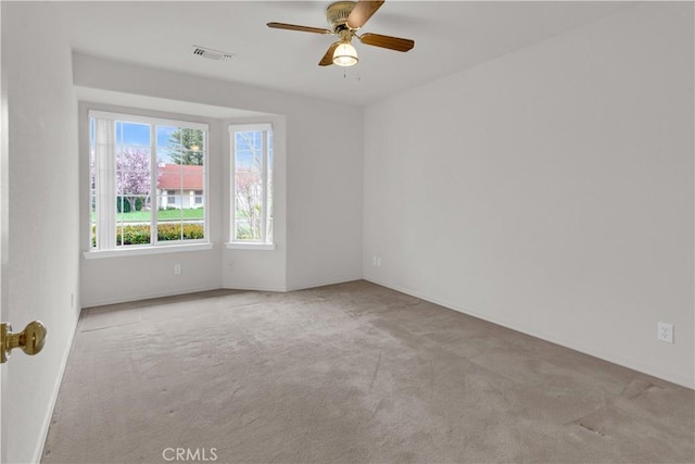 empty room with a ceiling fan, visible vents, and carpet