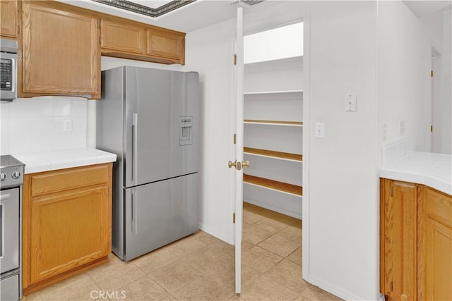 kitchen with tile counters, tasteful backsplash, and stainless steel appliances