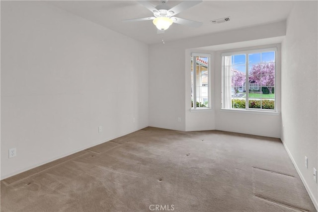 carpeted spare room with visible vents and a ceiling fan