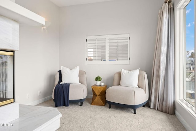 sitting room with plenty of natural light, light colored carpet, and baseboards