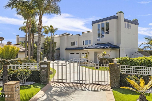 view of front of home featuring a fenced front yard, stucco siding, concrete driveway, and a gate