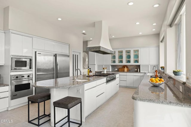 kitchen with modern cabinets, custom range hood, a sink, decorative backsplash, and built in appliances