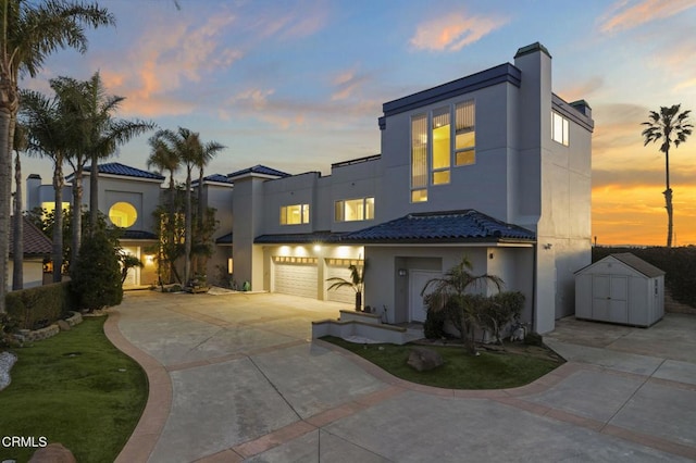 view of front of house with a shed, concrete driveway, stucco siding, a garage, and an outdoor structure