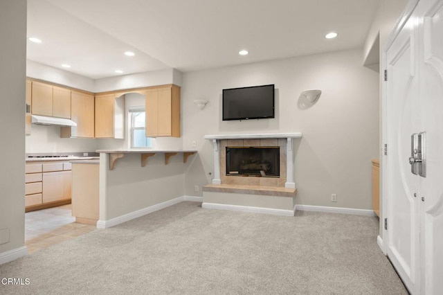 kitchen with a breakfast bar area, light brown cabinets, recessed lighting, under cabinet range hood, and light carpet