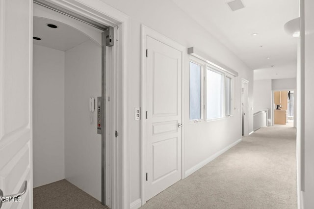 hallway with elevator and carpet