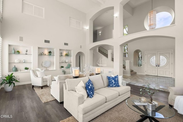 living area with built in features, stairway, dark wood-type flooring, and visible vents