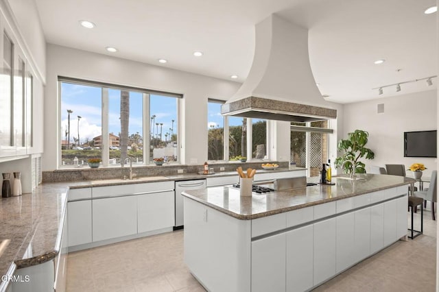 kitchen with dishwasher, stone countertops, white cabinetry, and island range hood