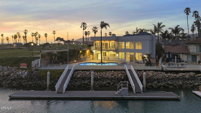 rear view of property featuring a patio area, an outdoor pool, and a water view