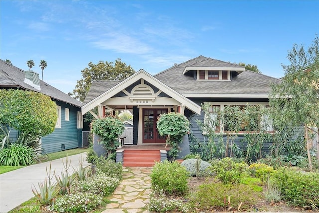 view of front of home featuring concrete driveway, french doors, and a shingled roof