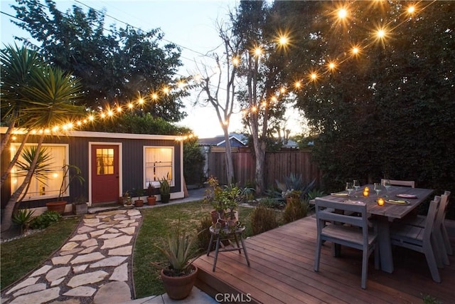 wooden deck featuring an outbuilding, outdoor dining area, and fence