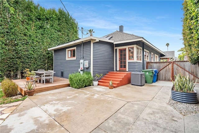 rear view of property with fence, a wooden deck, central AC unit, a chimney, and outdoor dining area