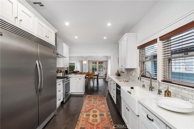 kitchen with visible vents, appliances with stainless steel finishes, dark wood-style floors, white cabinets, and a sink