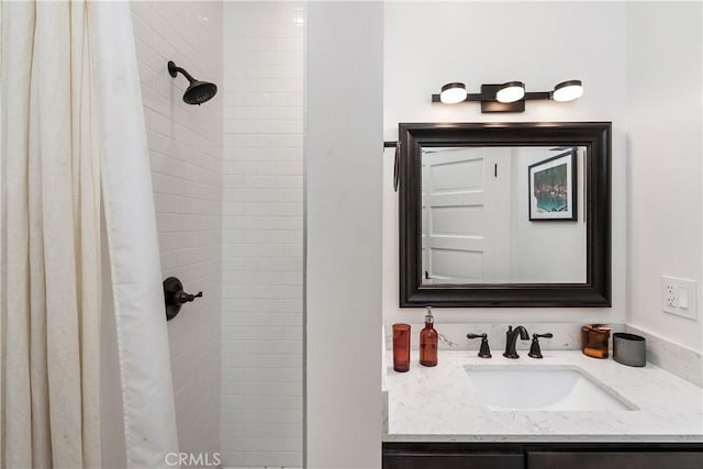 full bathroom with tiled shower and vanity