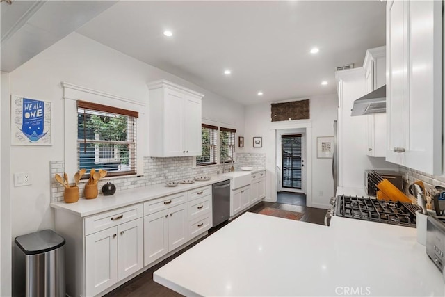 kitchen with under cabinet range hood, decorative backsplash, white cabinets, and light countertops