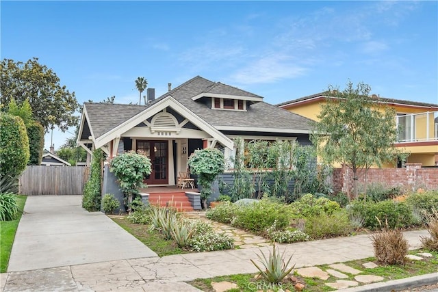 view of front of home with stucco siding, french doors, a shingled roof, and fence