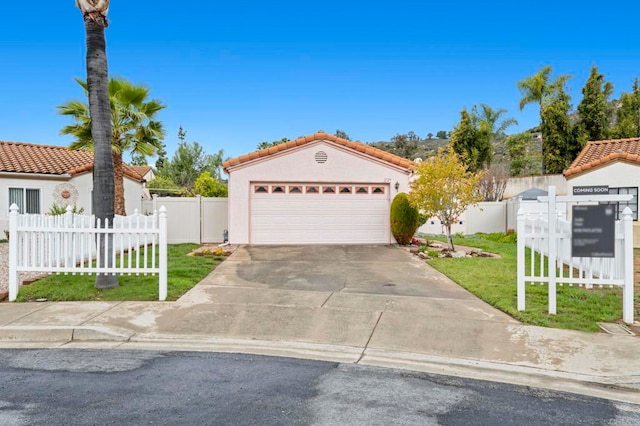 mediterranean / spanish home featuring stucco siding, concrete driveway, a front yard, and fence