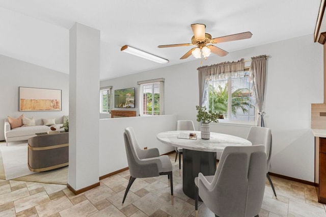 dining space featuring stone finish flooring, baseboards, lofted ceiling, and a ceiling fan