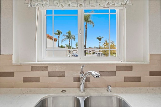 details featuring a sink, light stone countertops, and backsplash