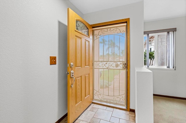 entrance foyer featuring baseboards and light colored carpet