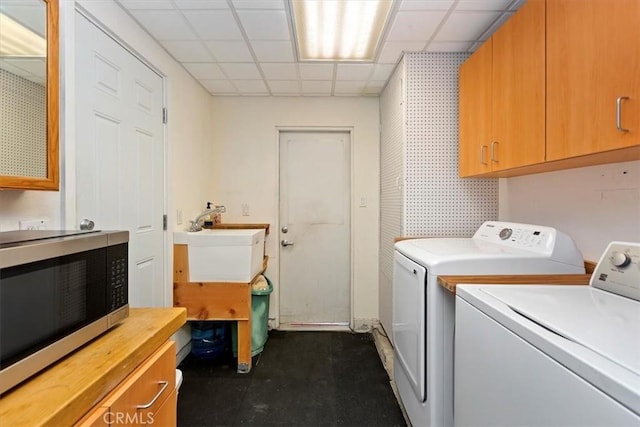 laundry area with cabinet space, washing machine and dryer, and a sink