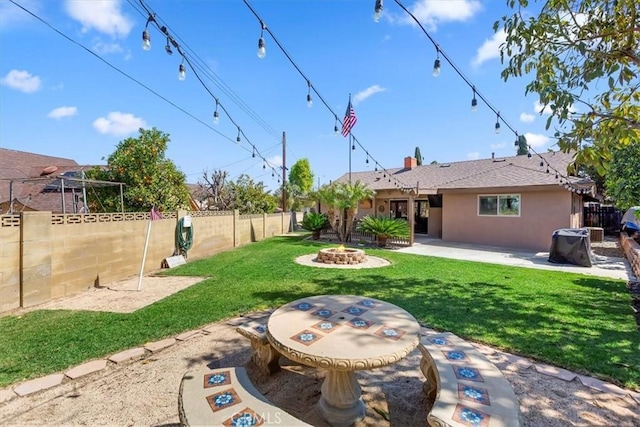 view of yard with a patio, a fenced backyard, and an outdoor fire pit