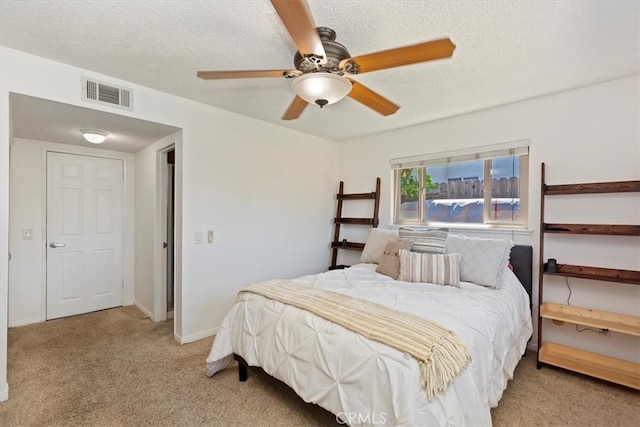 bedroom with visible vents, light colored carpet, a textured ceiling, and baseboards