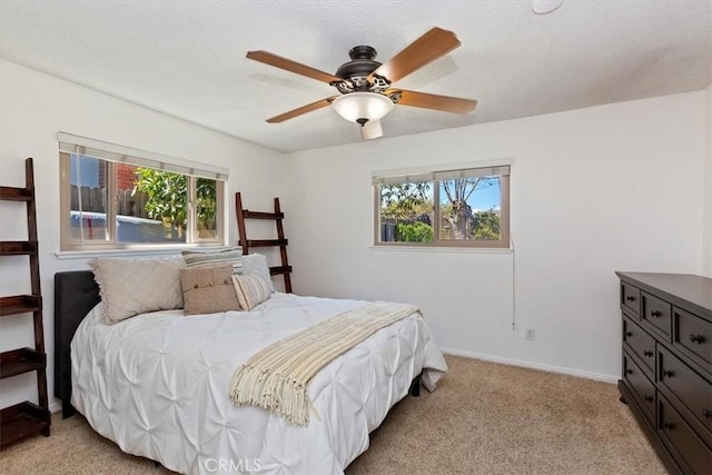 bedroom with light colored carpet, a textured ceiling, baseboards, and ceiling fan