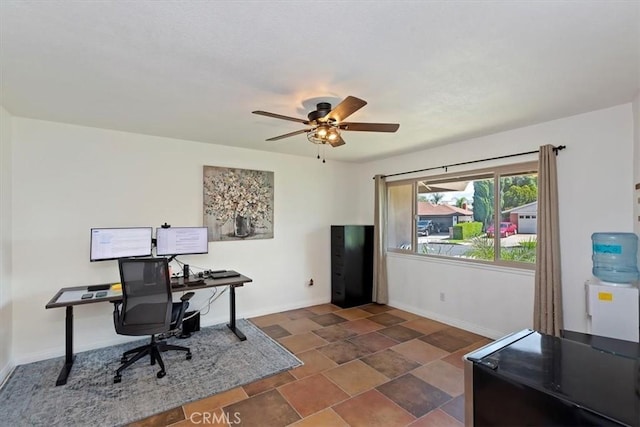 office area with a ceiling fan, baseboards, and stone finish flooring