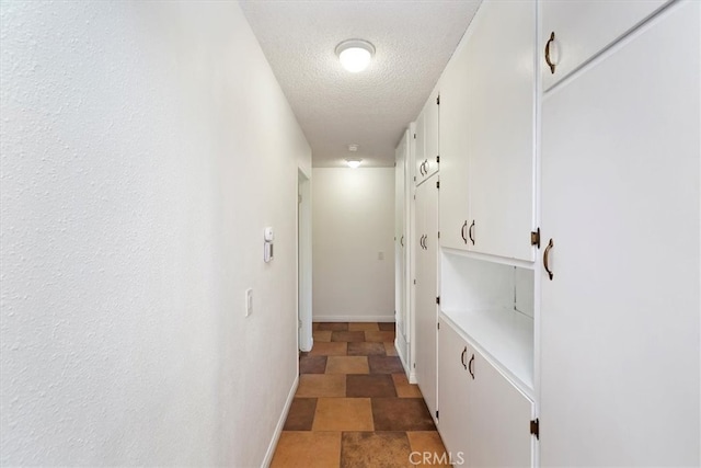 hallway featuring baseboards and a textured ceiling