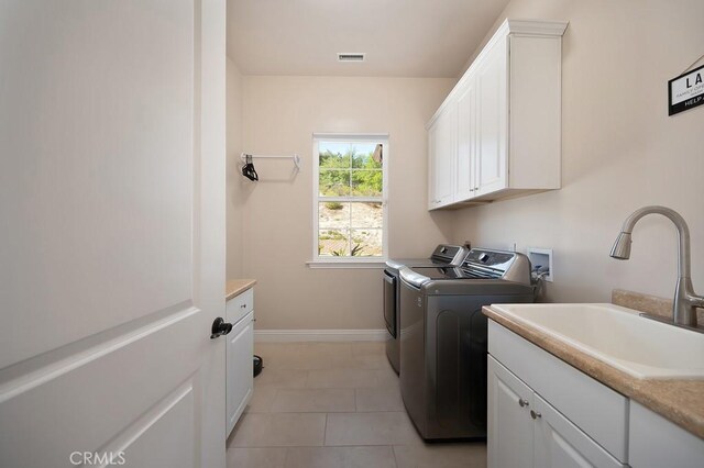 laundry room featuring washer and clothes dryer, a sink, cabinet space, light tile patterned floors, and baseboards