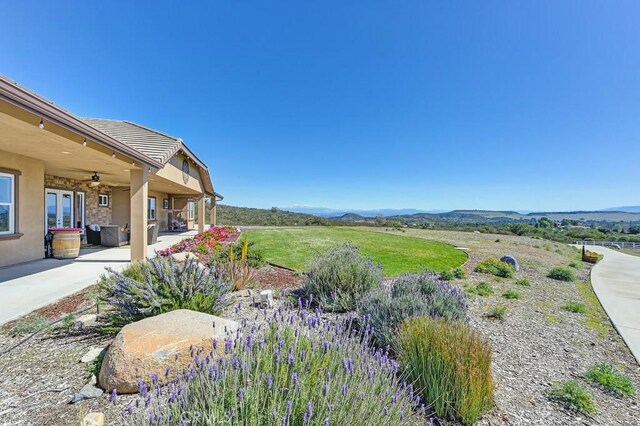 view of yard with a mountain view, a ceiling fan, and a patio area