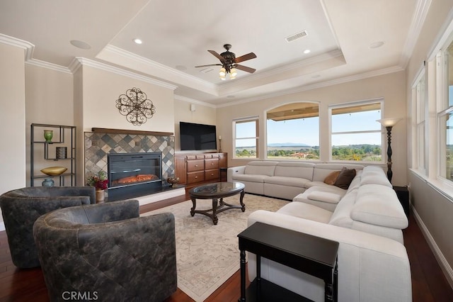 living area featuring visible vents, a raised ceiling, wood finished floors, and a fireplace