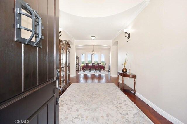 foyer entrance featuring arched walkways, dark wood-style floors, and ornamental molding