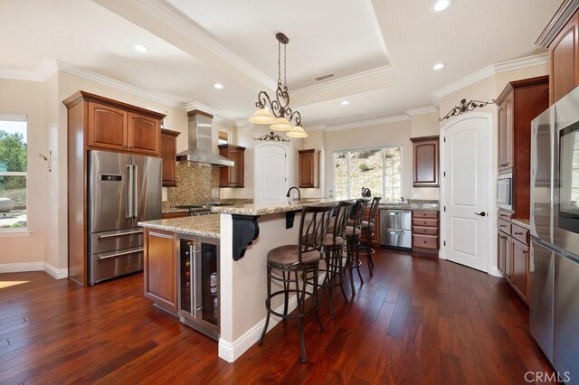 kitchen featuring visible vents, a kitchen island with sink, beverage cooler, stainless steel appliances, and wall chimney exhaust hood