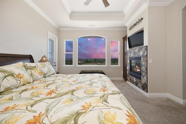 bedroom featuring visible vents, a tile fireplace, crown molding, a raised ceiling, and light colored carpet