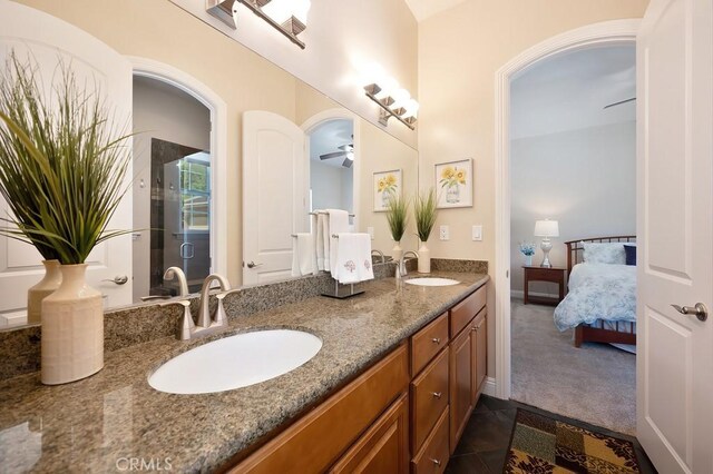 ensuite bathroom with double vanity, connected bathroom, a ceiling fan, and a sink