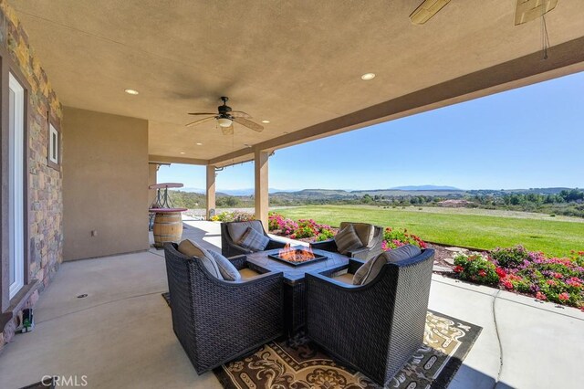 view of patio featuring an outdoor living space with a fire pit, a mountain view, and ceiling fan