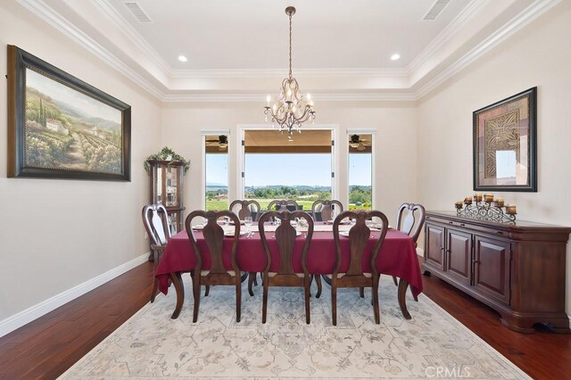 dining room with visible vents, wood finished floors, baseboards, and ornamental molding