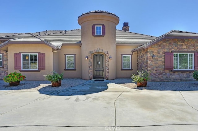 mediterranean / spanish-style house with a tiled roof, stone siding, and stucco siding