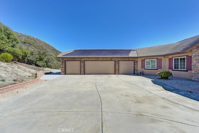 single story home with concrete driveway, a tiled roof, an attached garage, and stucco siding