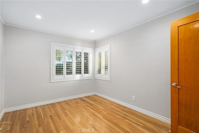 spare room featuring baseboards, crown molding, and light wood finished floors