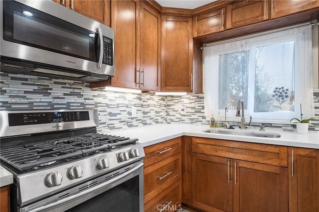 kitchen featuring brown cabinets, appliances with stainless steel finishes, light countertops, and a sink