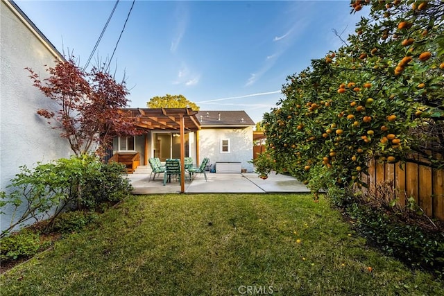 rear view of property featuring a patio, a yard, fence, and stucco siding