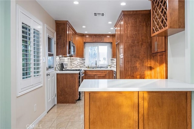 kitchen with visible vents, light countertops, appliances with stainless steel finishes, brown cabinets, and backsplash