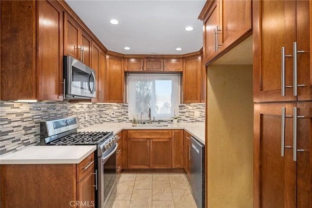 kitchen with a sink, stainless steel appliances, brown cabinets, and light countertops