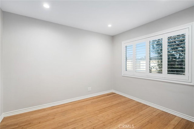 spare room featuring recessed lighting, light wood-type flooring, and baseboards