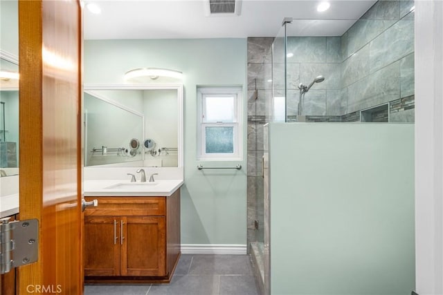 bathroom featuring tile patterned floors, visible vents, a tile shower, baseboards, and vanity