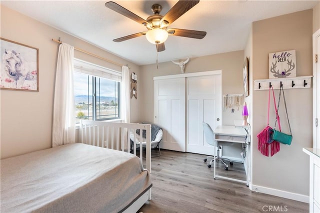 bedroom featuring ceiling fan, wood finished floors, a closet, and baseboards