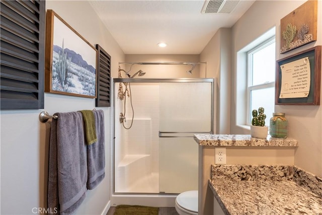 bathroom featuring visible vents, toilet, and a shower stall